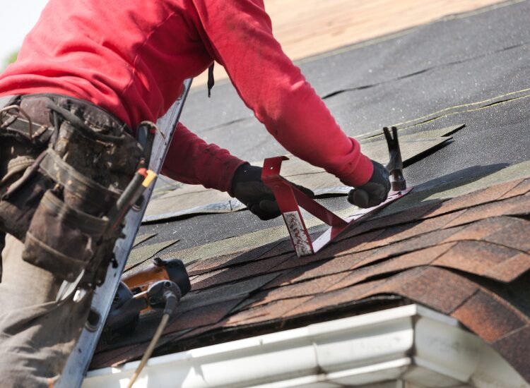 Roof Repair Howell NJ - roofing contractor in a red shirt repairing a residential roof.